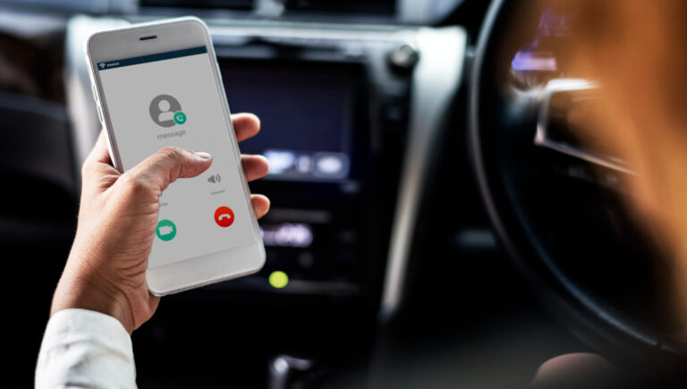 Persona en coche revisando llamada de compañía de seguros en su móvil