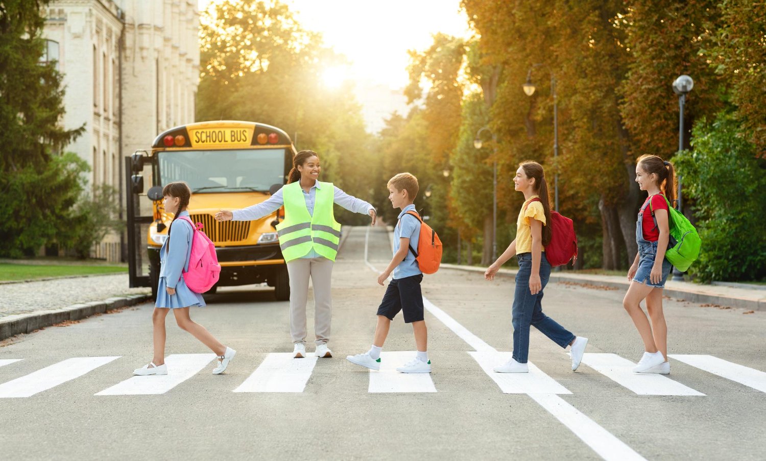 Niños cruzan la calle con un guardia escolar frente a un autobús escolar